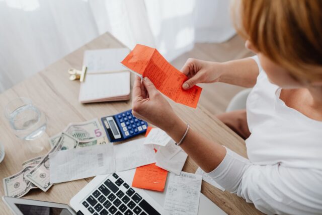 Factură, calculator și pix pe un birou, simbol al facturării și încasărilor unui freelancer