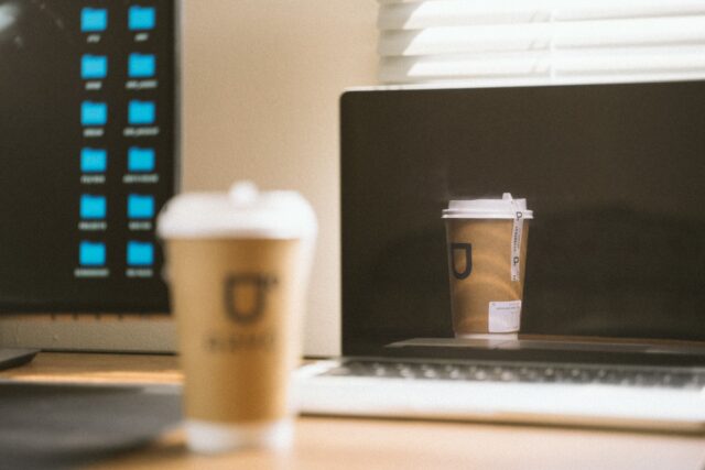 Laptop deschis și o ceașcă de cafea pe un birou, în timp ce se pregătește un newsletter